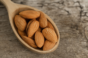 peeled almonds in spoon on wooden background. For vegetarians