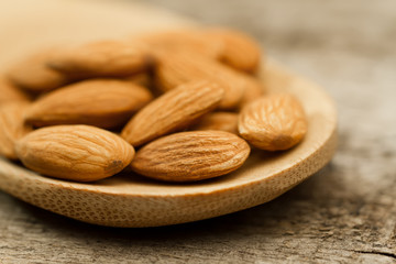 peeled almonds in spoon on wooden background. For vegetarians