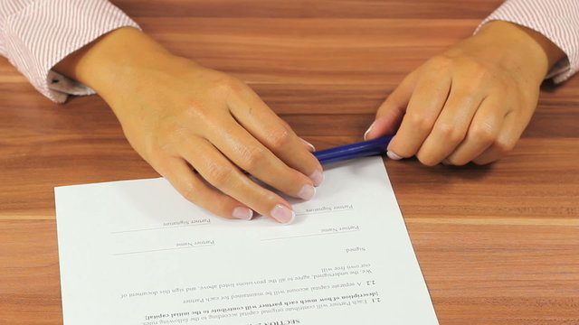 Woman signing a contract - Unrecognizable person signs a legal document using a fountain pen