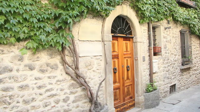 Beautiful front door of a stone-house in a narrow, shady street in an old Italian town.