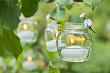 Kerze im Glass hängt im Baum