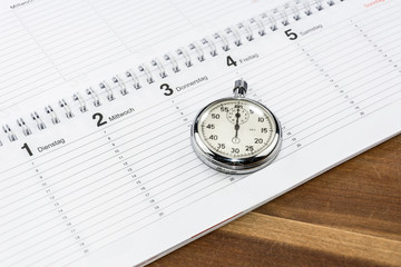 Stoppuhr liegt auf Terminkalender als Symbol für Zeitmanagement oder Terminplanung - obrazy, fototapety, plakaty