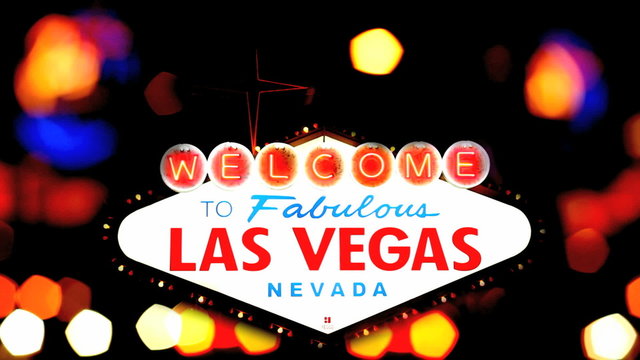 Lights of Las Vegas - Glowing welcome to Las Vegas sign in front of moving blurry traffic lights, useful for concepts based on Vegas, luck, tourists and traffic