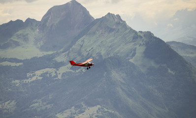 a small red airplane flying over the French Alps