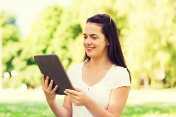 smiling young girl with tablet pc sitting on grass