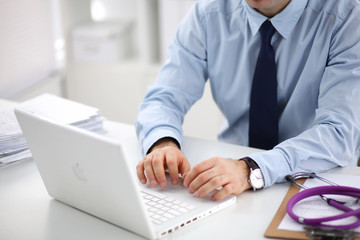 Doctor at work, close up of male doctor typing on a laptop