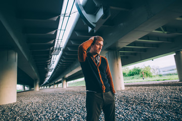 Young fashion man standing under a bridge