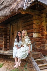 Ukrainian girls in national costumes at the wooden house