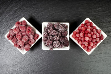 Drei Sorten gefrorene Beerenfr&uuml;chte in Porzellanschalen