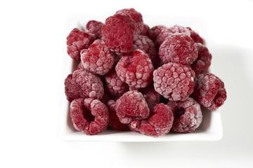 Gefrorene Himbeeren in Porzellanschale auf weißem Hintergrund
