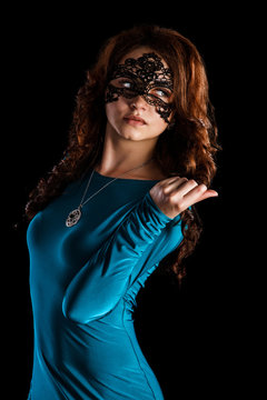 Beautiful young woman in a black mask and a green dress