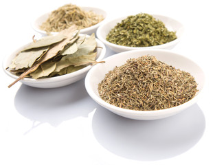 Rosemary, parsley, bay leaves and thyme in white bowl over white background