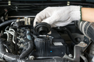 A mechanic is opening the oil cap from a car engine.