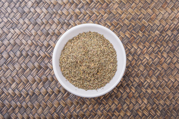Thyme herb in white bowl over wicker background