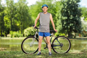 Obraz premium Senior biker standing by a pond in a park
