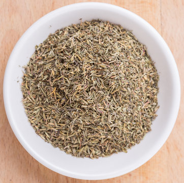 Thyme herb in white bowl over wooden background