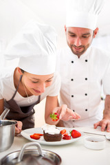 Young chef training a young attractive girl to cook
