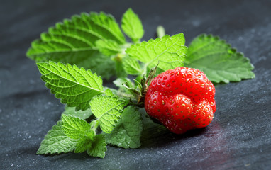 Fresh strawberries with mint leaves on a dark gray background, s
