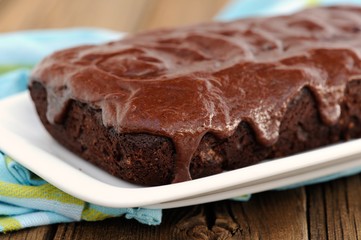 Dark chocolate cake with leaky chocolate icing in white plate