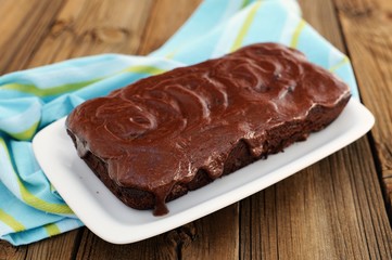 Dark chocolate cake with leaky chocolate icing in white plate