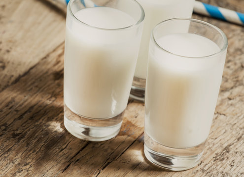 Three glasses of fresh milk on old wooden table in rustic style,