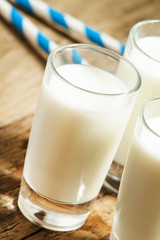 Three glasses of fresh milk on old wooden table in rustic style,