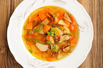 Porcini mushroom soup with potato and carrot in white plate on w