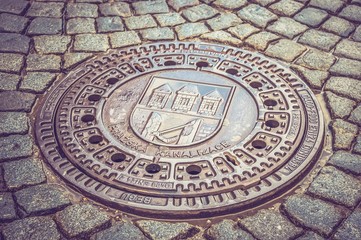 Metal hatch sewer manhole and cobblestone pavement