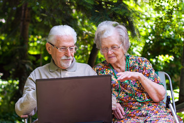 Elderly couple having fun with the laptop outdoors