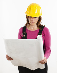 Studio shot of a female construction worker looking at house plans on white background.