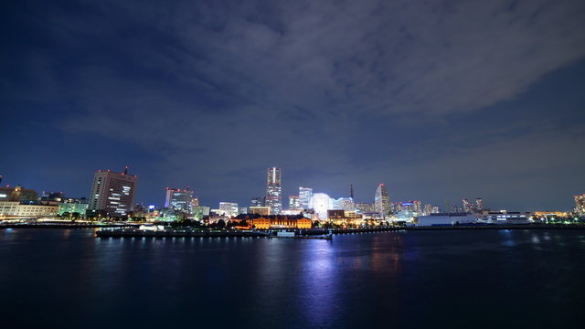 Time lapse footage with zoom in motion of metropolitan city skyline over the bay at night in Yokohama, Japan