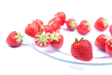 Several randomly distributed strawberries on a transparent plate