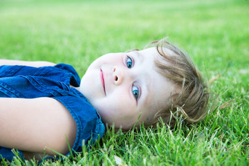 Little adorable girl lying on grass