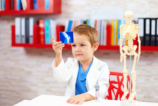 cute kid playing a doctor, looking at x-ray image of leg