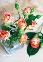 beautiful bouquet of roses in glass on wooden table
