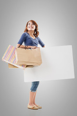 Shopping woman holding bags and blank board