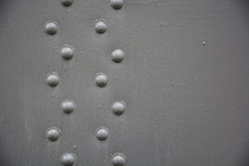 Fototapeta na wymiar Grey metal background with rivets. Closeup view