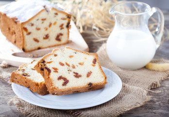 Cake with raisins, sprinkled with powdered sugar and jug of milk