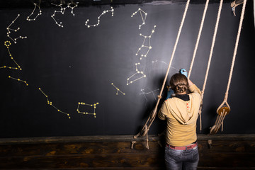 Woman Painting Star Constellations on Blackboard