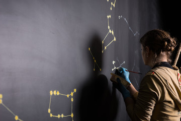 Woman Painting Star Constellations on Black Board