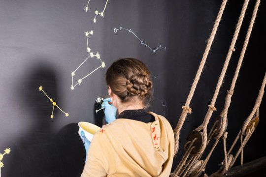 Woman Painting Star Constellations on Blackboard