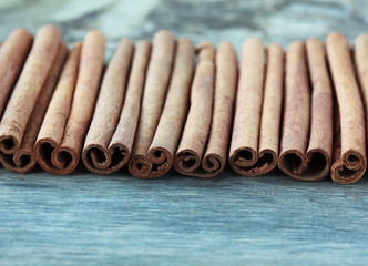 row of cinnamon sticks on an old wooden table background, select