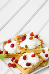waffles with wild strawberries and whipped cream on white table