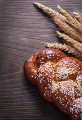 Baked bun wheat rye ears on wooden board food and drink concept