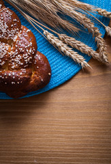 Obraz na płótnie Canvas Fresh-baked bun wheat rye ears with wicker table-cloth on wooden