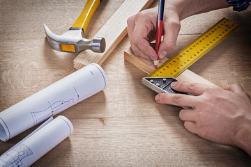 hands of carpenter drawing with pencil on wooden plank