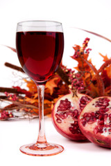Pomegranate Juice in Wine Glass – Pomegranate juice served in a wine glass. Pomegranates and autumn decorations shown in background.