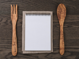 notebook with spring on wood table with wooden utensils for