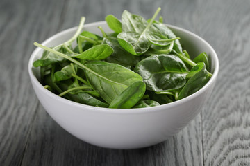 fresh spinach leaves in white bowl on wood table