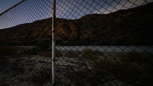  Motion controlled dolly time lapse footage with dolly down motion of traffic lights on Pacific Coast Highway at night shot through fence in Malibu Beach, California